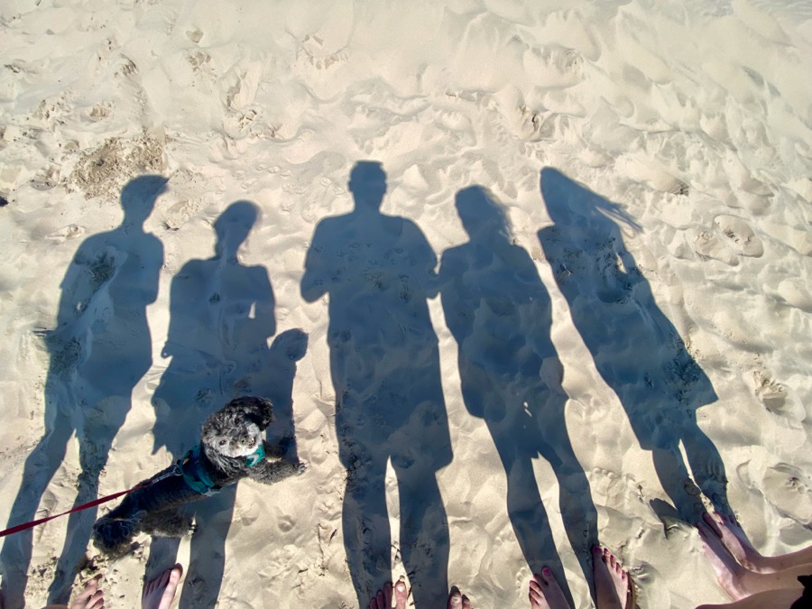 Rodina na pláži – stíny Romana, manželky, tří dětí a psa